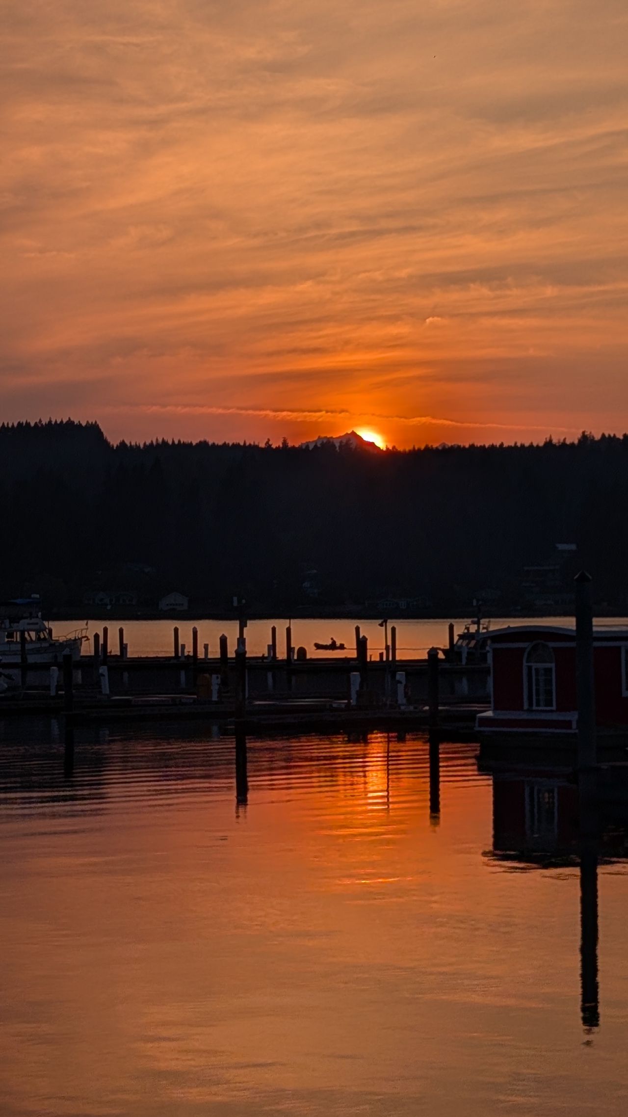 Brilliant orange sunset reflecting in the calm water of Poulsbo harbour with docks and boats silhouetted