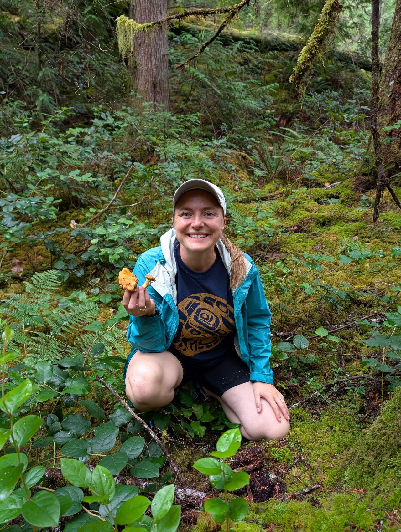 Rachel holding a chanterelle while foraging in the mossy forest